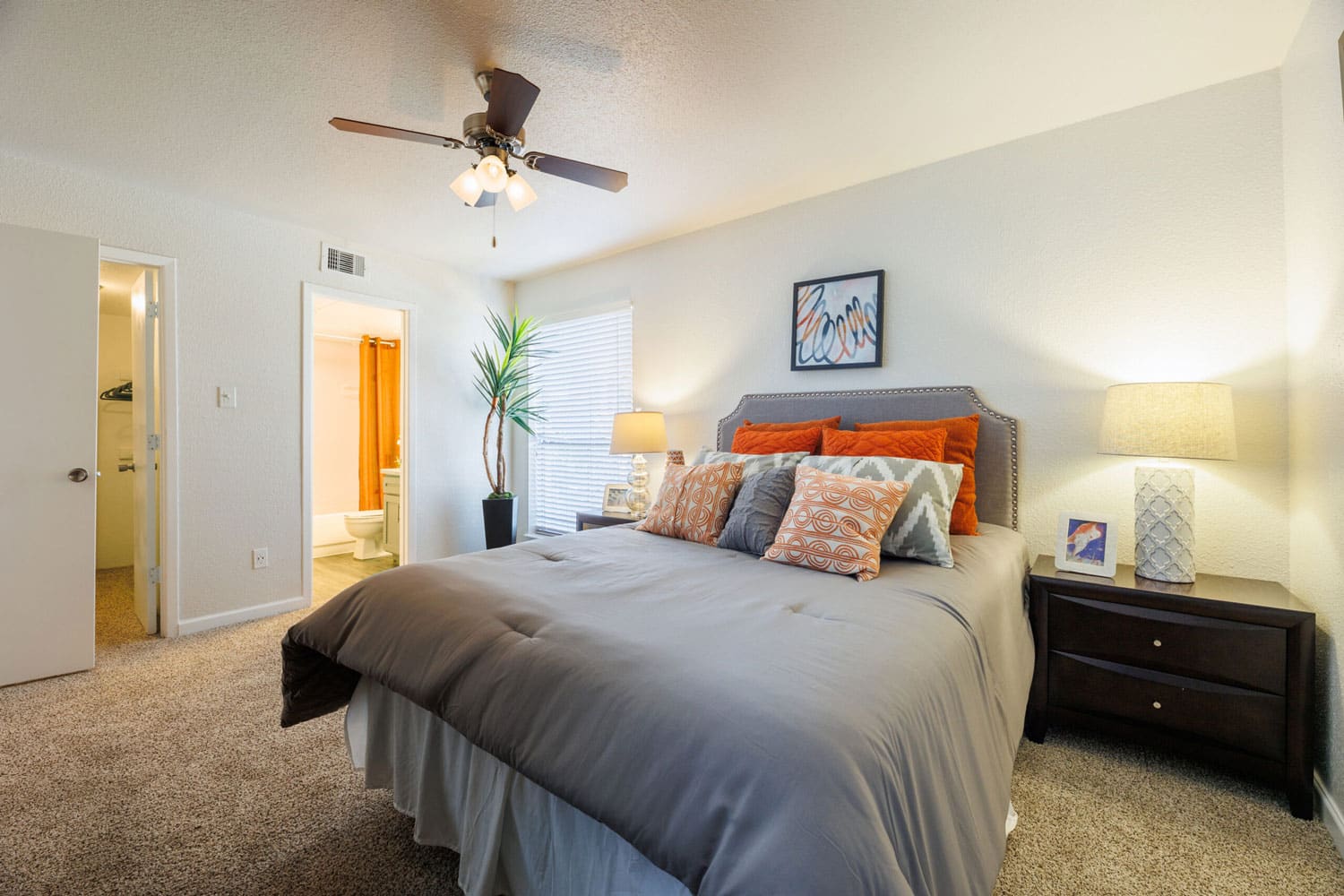 Master bedroom with en-suite bathroom and ceiling fan at The Brook on Bay Area apartments Webster TX